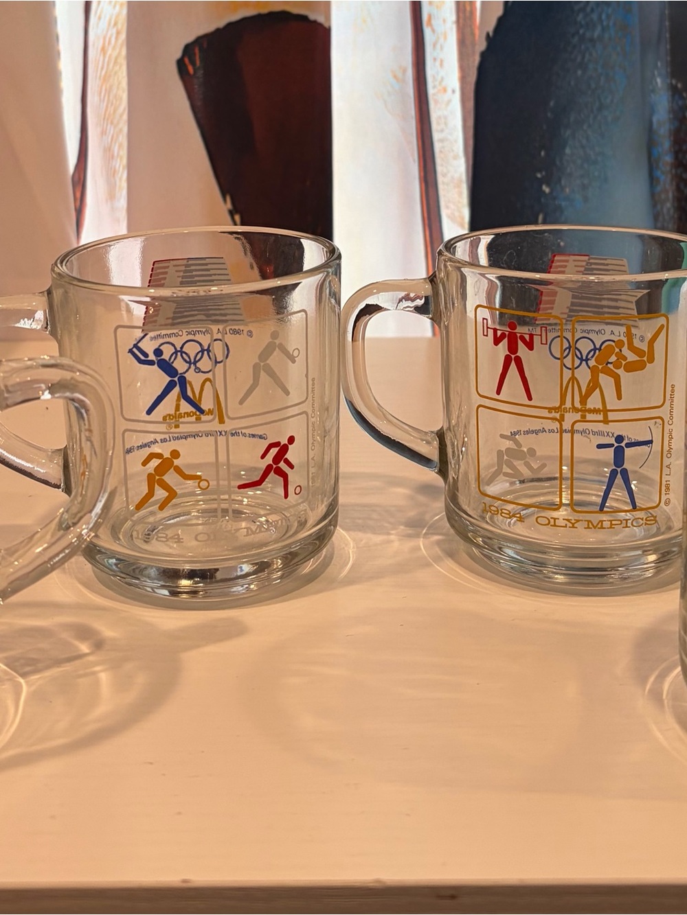 McDonald's Clear Glass Mugs with Red, Blue, Yellow, and Gray Olympic Icons